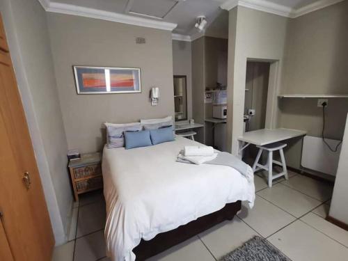 布隆方丹Namib Dlux Corporate Group Accommodation的一间带一张床和一张书桌的卧室和一间厨房