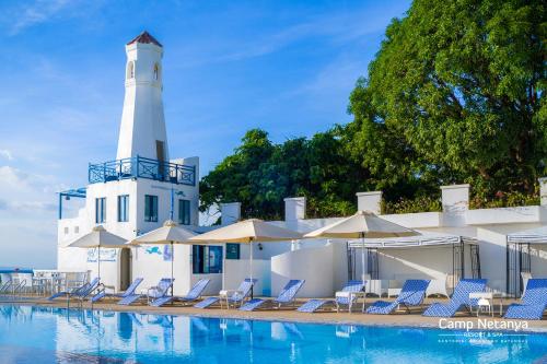马比尼内坦亚营地度假酒店及Spa的一个带椅子的游泳池和一个位于后面的灯塔