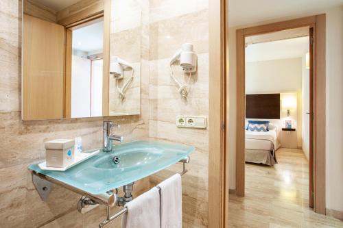 坎皮卡福特Grupotel Dunamar的一间带蓝色水槽的浴室和一间卧室
