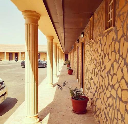 Al GhāţDesert Rose Motel的有一排柱子在有盆栽植物的建筑物上