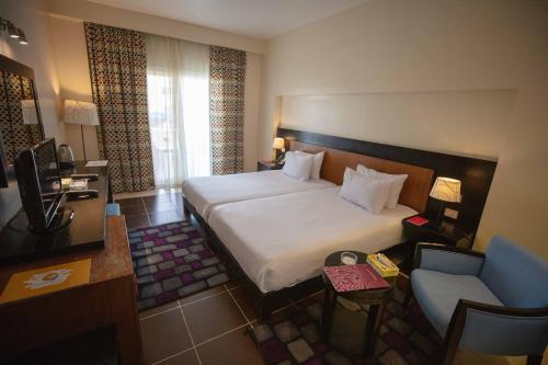 拉斯苏德尔Mousa Coast Hotel & Spa的配有一张床和一把椅子的酒店客房