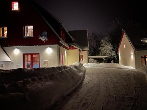 FürstenauZur Bergwiese 5 Sterne Appartementhaus的夜晚在房子前面的一条雪覆盖的街道