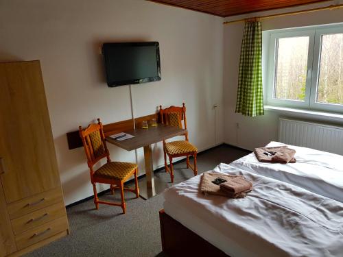 塔查斯卡-鲁穆尼卡萨散卡酒店的一间卧室配有两张床、一张桌子和一台电视。
