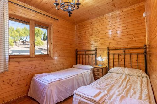 AledoALEDORURAL的小木屋内的两张床,设有窗户