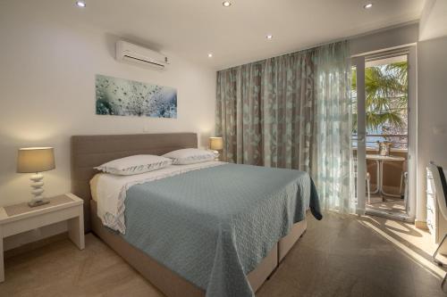 马卡尔斯卡Apartments Bogica的一间卧室配有一张带蓝色毯子的床和窗户。