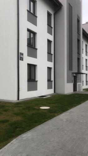 马尔堡Apartament Gościnne Sady的一座白色的建筑,旁边是一座草地庭院