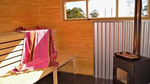 亚特兰蒂斯达La Chacra Holandesa的小木屋设有长凳和炉灶。