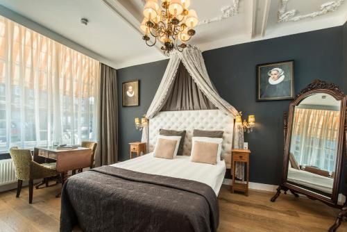 莱顿Boutique Hotel Huys van Leyden的一间卧室配有一张床、一张书桌和一个吊灯。