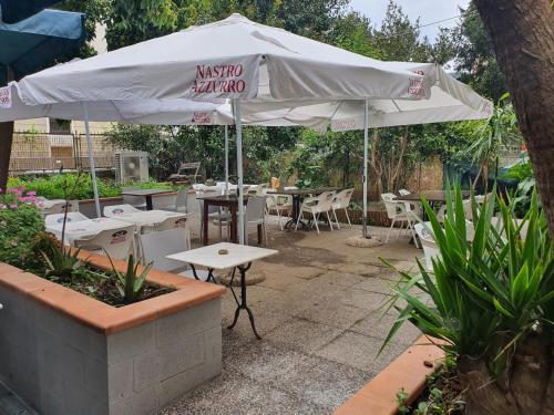 斯培西亚美丽那不勒斯旅馆及意大利比萨饼餐厅的一个带桌椅和遮阳伞的庭院