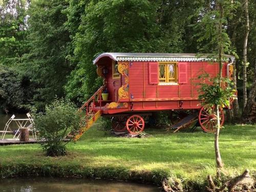 TroussuresLes Roulottes de Troussures的一条红火车坐在河边的草丛中