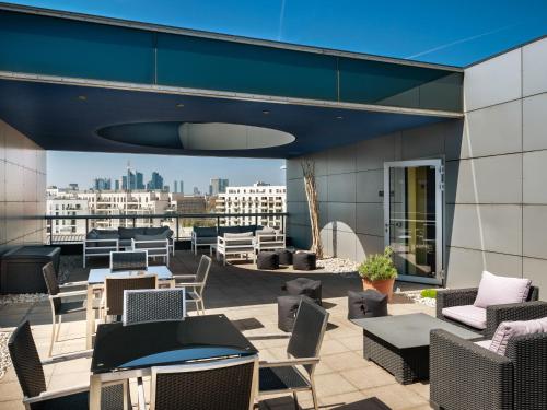 美因河畔法兰克福Plaza Hotel & Living Frankfurt的一个带桌椅的屋顶露台,享有城市美景