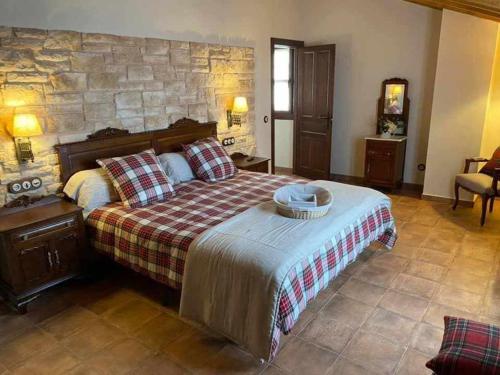 卢安科Casa Rural La Tayuela的一间卧室设有一张大床和石墙
