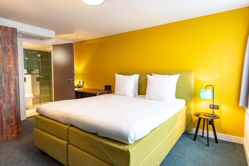 ZaandijkBoutique Hotel Zaan的一间卧室设有一张黄色墙壁的大床