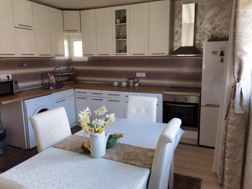 新瓦罗什Nikolaj Lux的厨房配有白色橱柜和鲜花桌