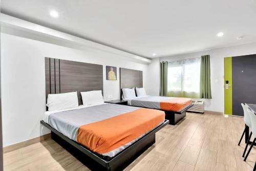 LakewoodExclusivo Inn and Suites的酒店客房配有两张床和一张书桌