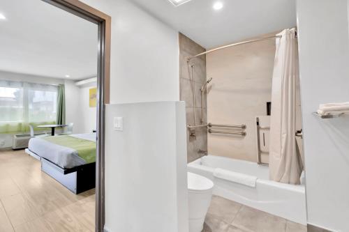 LakewoodExclusivo Inn and Suites的一间带床、浴缸和卫生间的浴室