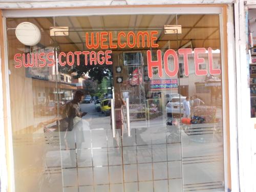 伊斯兰堡Swiss Cottage Hotel的商店的窗户,上面有一个人的反射