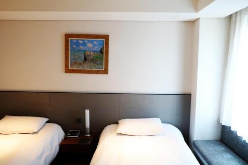 首尔明洞托马斯酒店的一间设有两张床的客房,墙上挂着一张照片