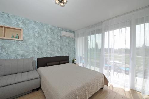 巴拉顿菲赖德Bella Flora Apartman的一间卧室配有一张床、一张沙发和一个窗口