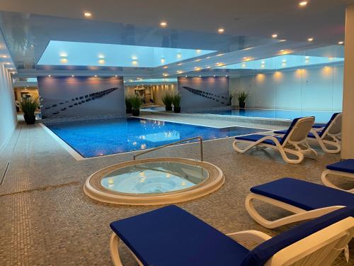 格但斯克Waterlane by Vivendi Properties的一个带椅子和热水浴缸的大型游泳池