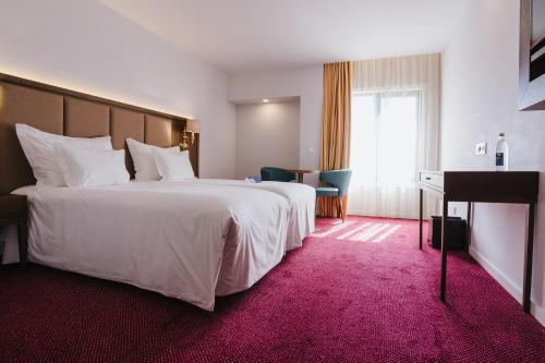 查韦斯Hotel Premium Chaves - Aquae Flaviae的酒店客房设有一张白色大床和一架钢琴