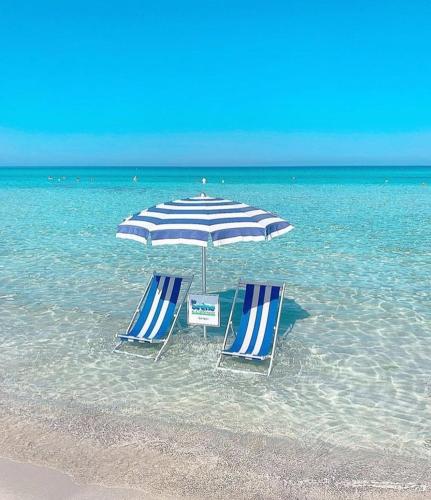 托雷莫泽Monolocale economy a 10m dal mare的海滩上的两把椅子和一把遮阳伞
