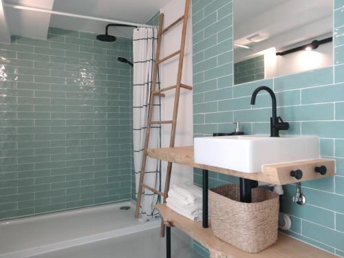 沙尔内卡Surf & Kite - Villa Nortada的浴室设有水槽和蓝色瓷砖淋浴。