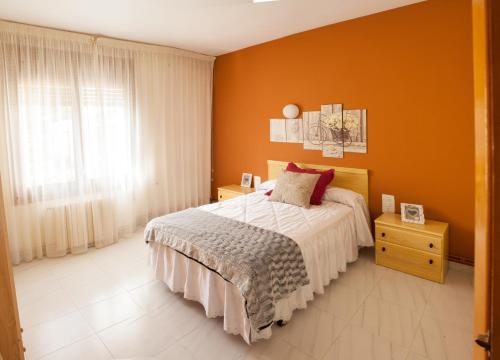 努瓦洛斯Apartamentos rurales La posada de Donato的一间卧室拥有橙色的墙壁、一张床和窗户