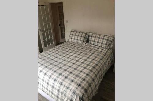 亚历山德里亚One bedroom Flat on the banks of Loch Lomond的一张带 ⁇ 子毯子的床铺