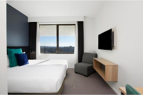 堪培拉曼特拉麦克阿瑟酒店的酒店客房带一张床、一台电视和一把椅子