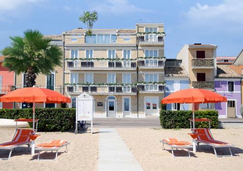 雷卡纳蒂港Opera Arte Suite Apartments的大楼前带椅子和遮阳伞的海滩