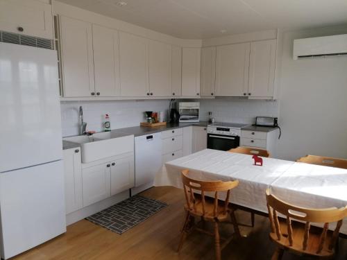 雷克桑德Dimgården的厨房配有白色橱柜和桌椅
