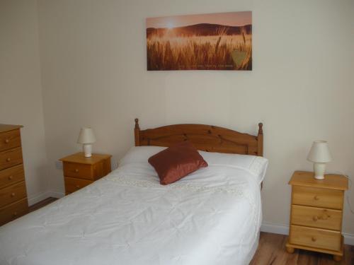 诺克Beautiful 3-Bed House in Knock的一间卧室配有一张白色床、两个床头柜和两盏灯。