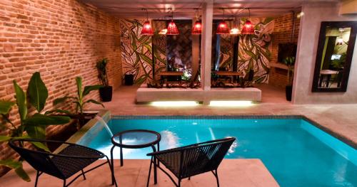 圣玛尔塔Oasis Fresh Hotel的一个带椅子和桌子的游泳池以及砖墙