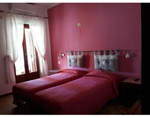 弗卡诺Hotel Torre的配有粉红色墙壁和窗户的客房内的两张床