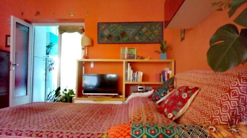 罗马4321 B&B Stazione Trastevere的一间卧室设有橙色的墙壁、一张床和电视