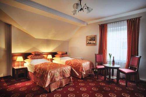 切霍齐内克哥白尼酒店的酒店客房带两张床和一张桌子以及椅子。