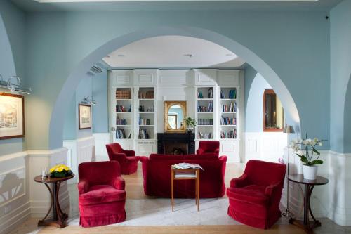 的里雅斯特马克西米利安里维埃拉酒店 的客厅设有红色椅子和拱门