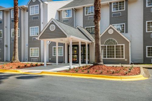 塔拉哈西Sleep Inn & Suites Tallahassee-Capitol的街道前方有棕榈树的建筑