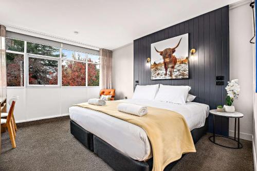 阿米代尔City Centre Motel Armidale的卧室配有一张大床,上面有一副牛的照片