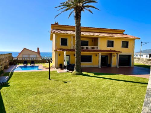 奥亚Casa Con Piscina Junto Al Mar的棕榈树和院子的黄色房子