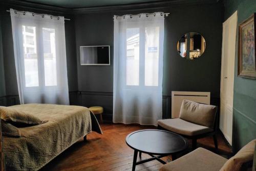 鲁昂Grand Studio de charme Rouen centre的一间卧室配有一张床、一把椅子和一张桌子