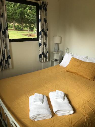圣阿诺山景顶级木屋的一间卧室配有一张床,上面有两条毛巾