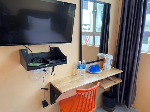 KapitLoft Pals Urbanstay Lodge, Kapit的墙上的电视机,配有木桌和椅子