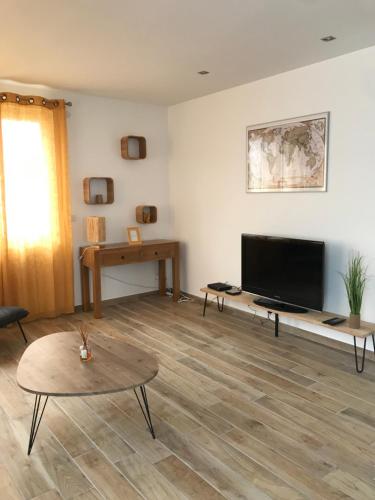 佩皮尼昂Cottage La Villa Sant Martí的客厅配有平面电视和桌子。