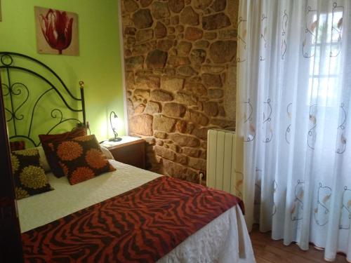 帕德隆Casa Rural A Eira Vella的一间卧室设有一张床和石墙