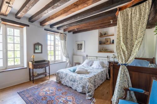 蒙特普利斯尚伯德Maison d'hôtes Moulin du Bas Pesé的卧室配有一张床、一张书桌和窗户。