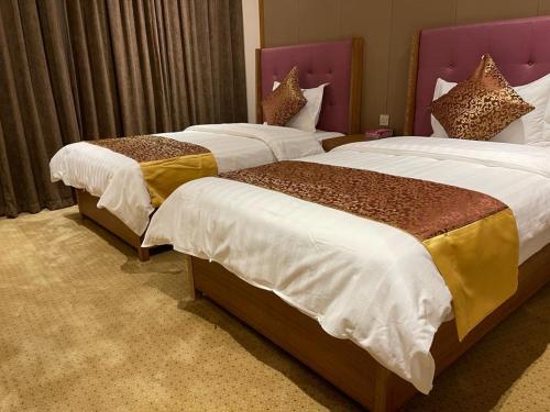 利雅德Hosta Hotel Suites的配有衬衫的酒店客房内的两张床
