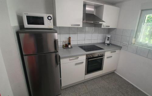 莱茵豪森Kleines Bauernhaus mit nostalgischem Flair的厨房配有不锈钢冰箱和微波炉。
