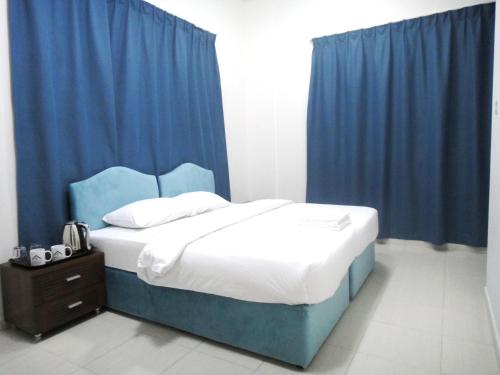迪拜Al Badaa Star Residence - Home Stay的一间卧室配有蓝色窗帘的床